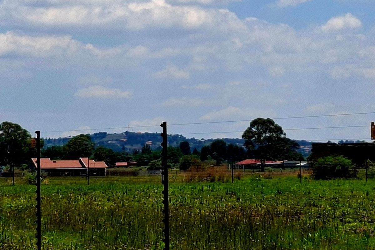 A view across the vacant residential land showing surrounding neighborhood landscape and electric fencing.