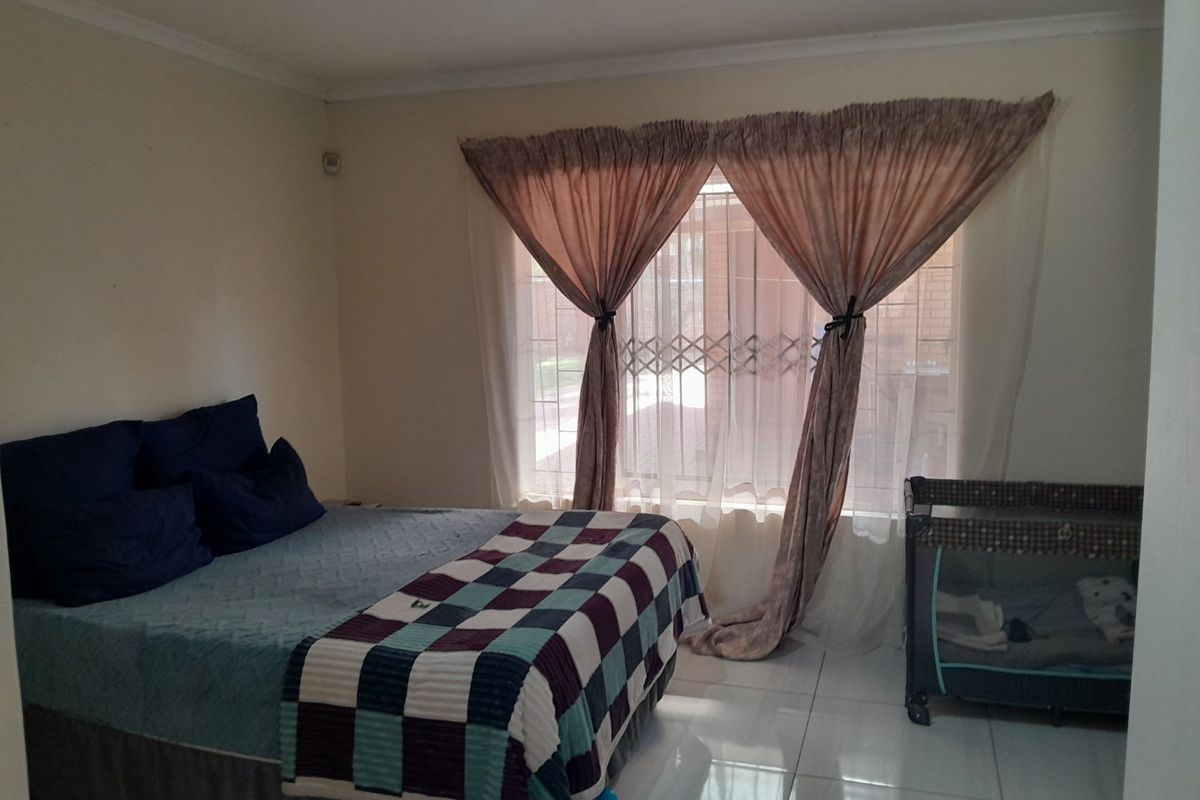 A bedroom featuring tiled flooring and a security gate installed on the window.