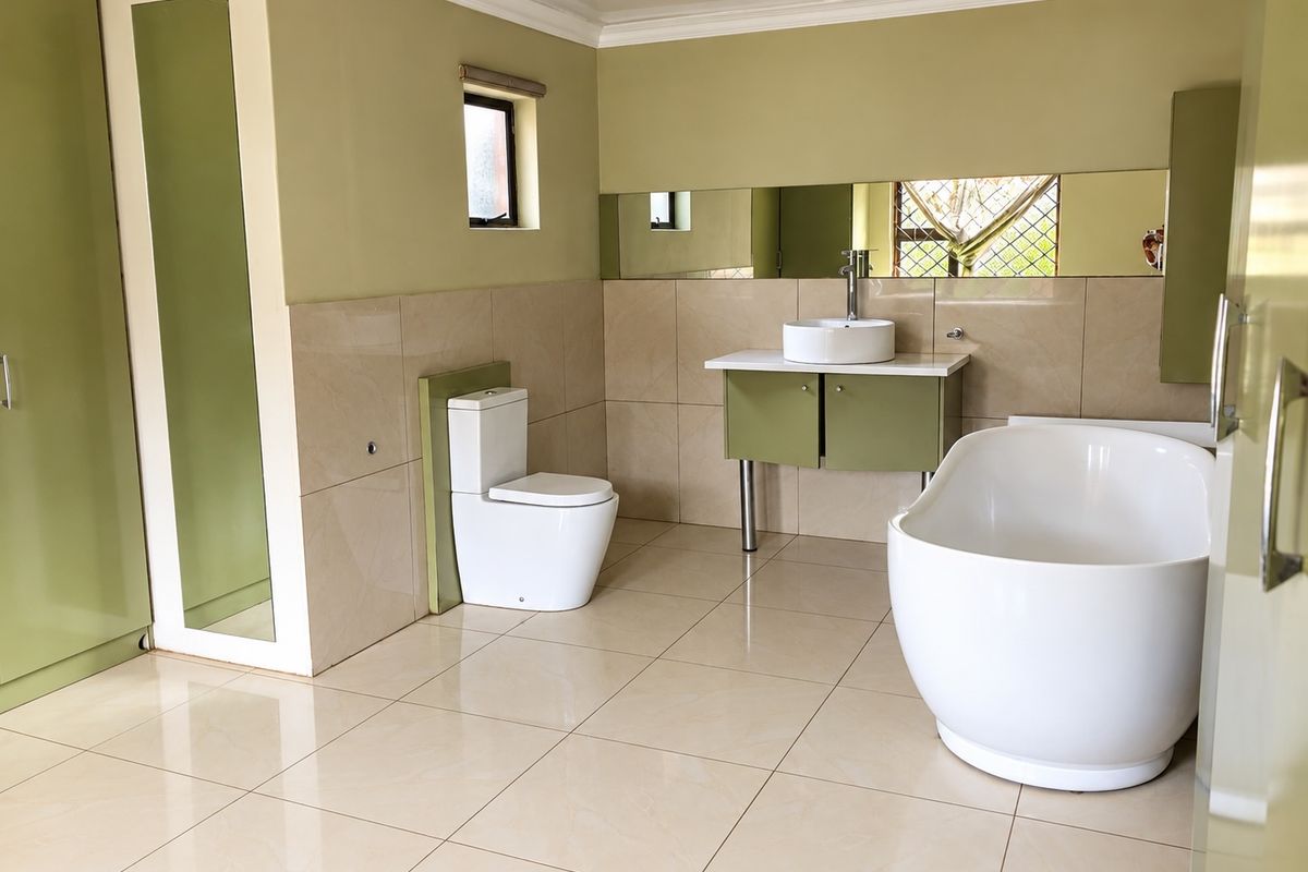 Spacious modern bathroom featuring a freestanding bathtub, vessel sink vanity, and neutral tiled finishes with ample built-in storage.