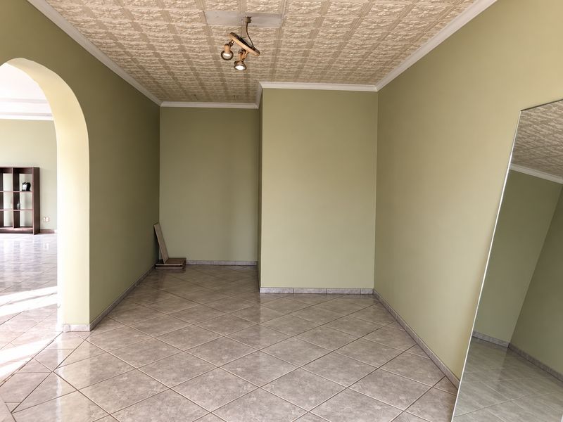 An empty living room featuring tiled flooring, a textured ceiling, and an arched entryway leading to an adjacent space.