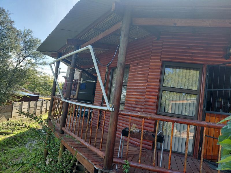 A rustic timber-clad balcony featuring a wooden deck, railing, and corrugated metal roof, providing an outdoor space with potential for enhancement.