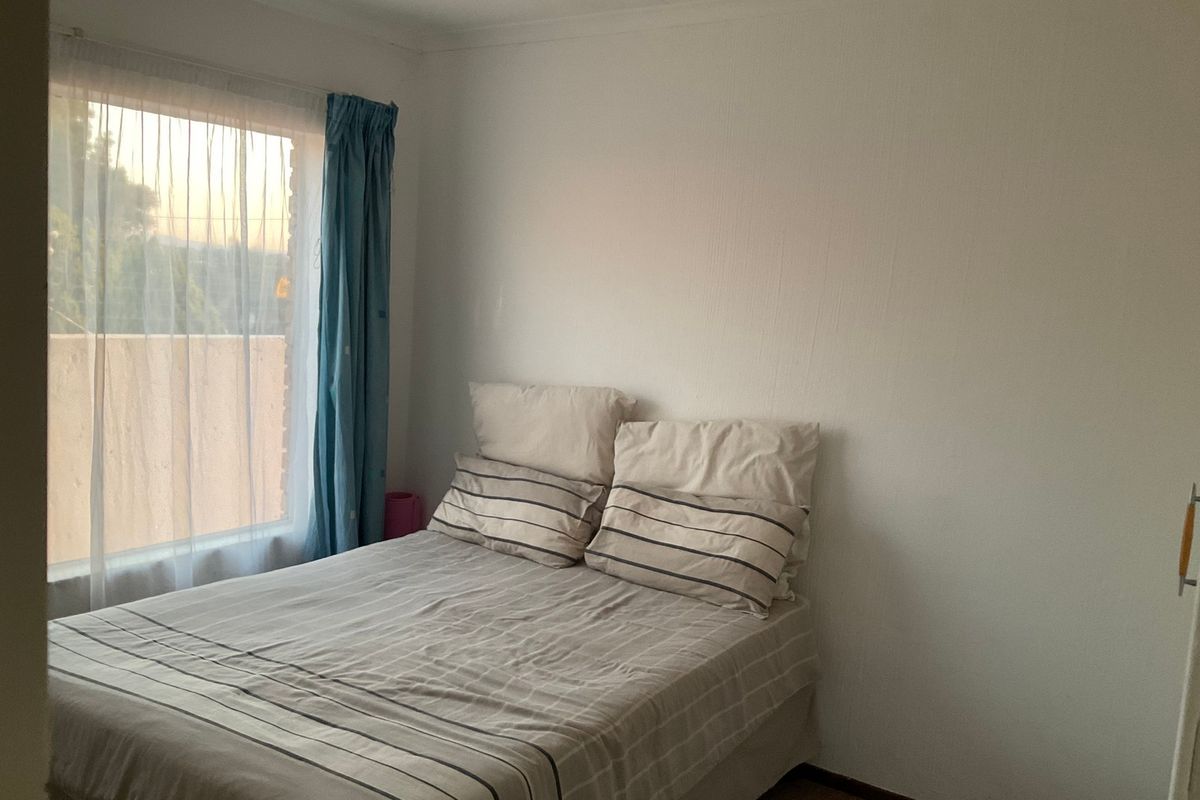 A standard bedroom featuring a window with natural light and a built-in cupboard, providing a functional living space.