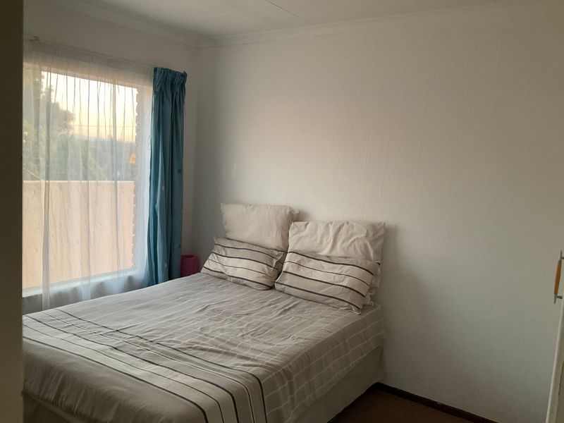 A standard bedroom featuring a window with natural light and a built-in cupboard, providing a functional living space.