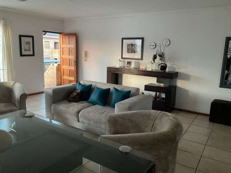 A well-lit living room featuring neutral tiled flooring and direct access to an exterior entrance area.