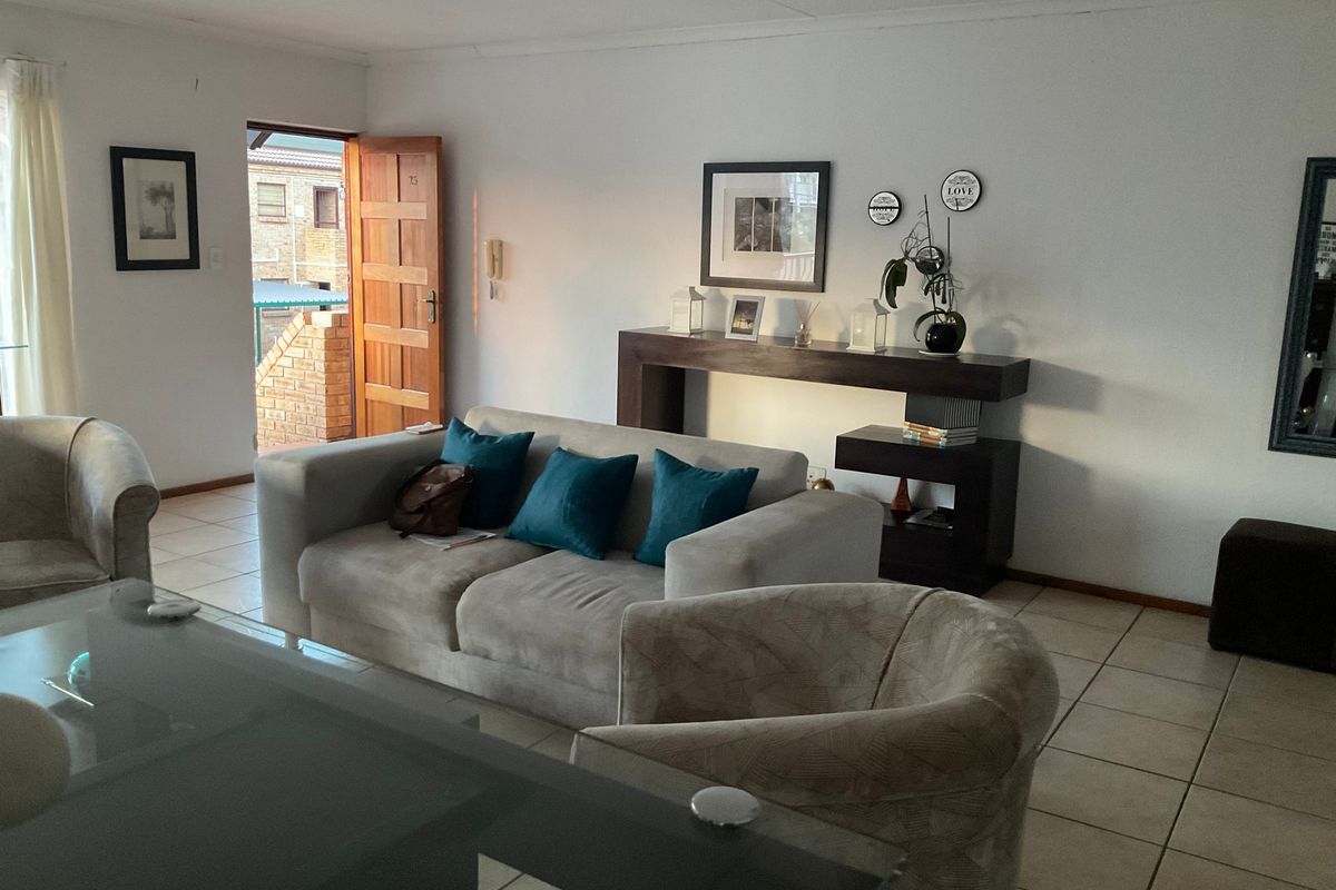 A well-lit living room featuring neutral tiled flooring and direct access to an exterior entrance area.