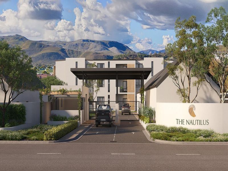 A modern apartment complex entrance featuring a secure gated access point, guard house, and landscaped surroundings with mountain views.