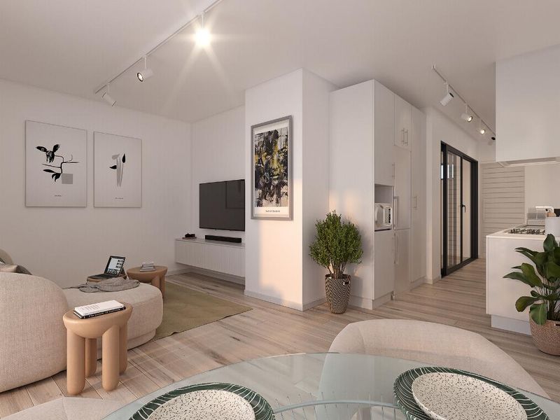 Modern open-plan living area featuring light wood flooring, track lighting, and a sleek kitchen with integrated appliances and built-in cabinetry.