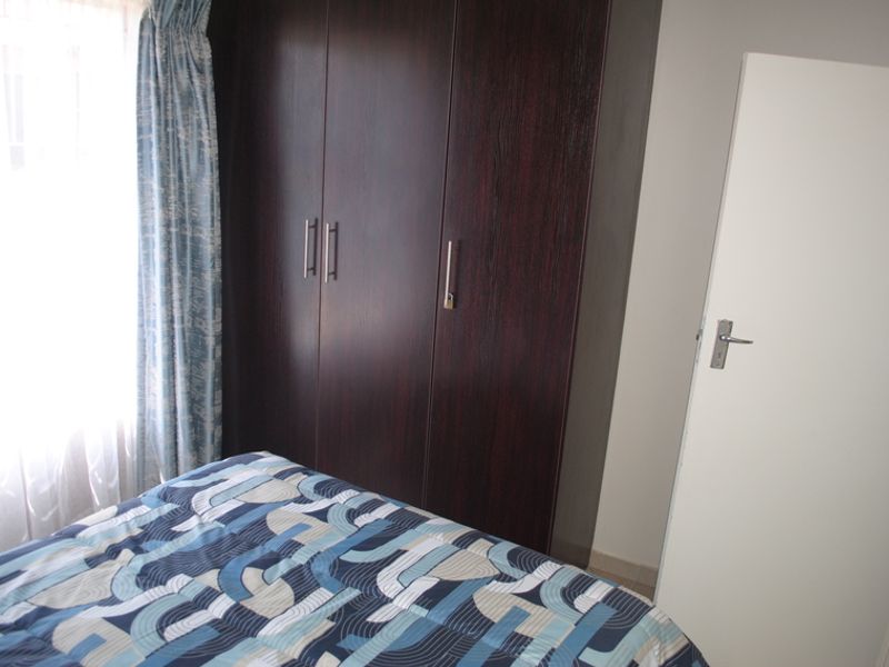 A bedroom featuring dark wood built-in cupboards and a standard internal door, providing functional storage space.