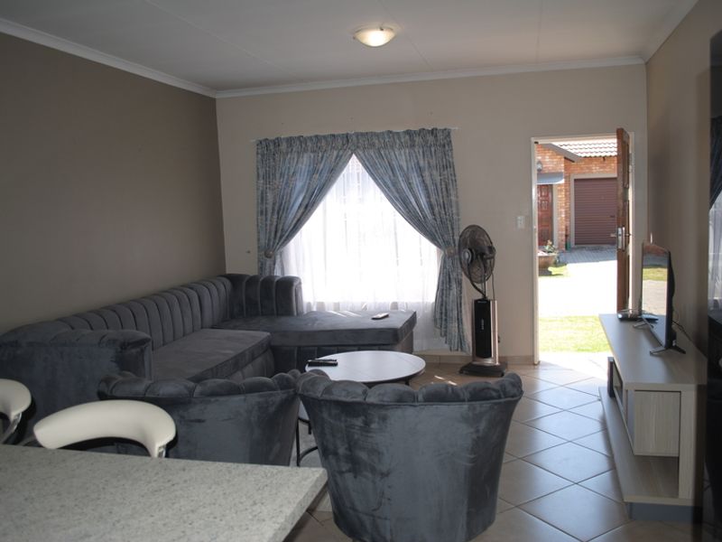 A living room area featuring tiled flooring and direct access to the exterior, providing a functional space with neutral wall tones.