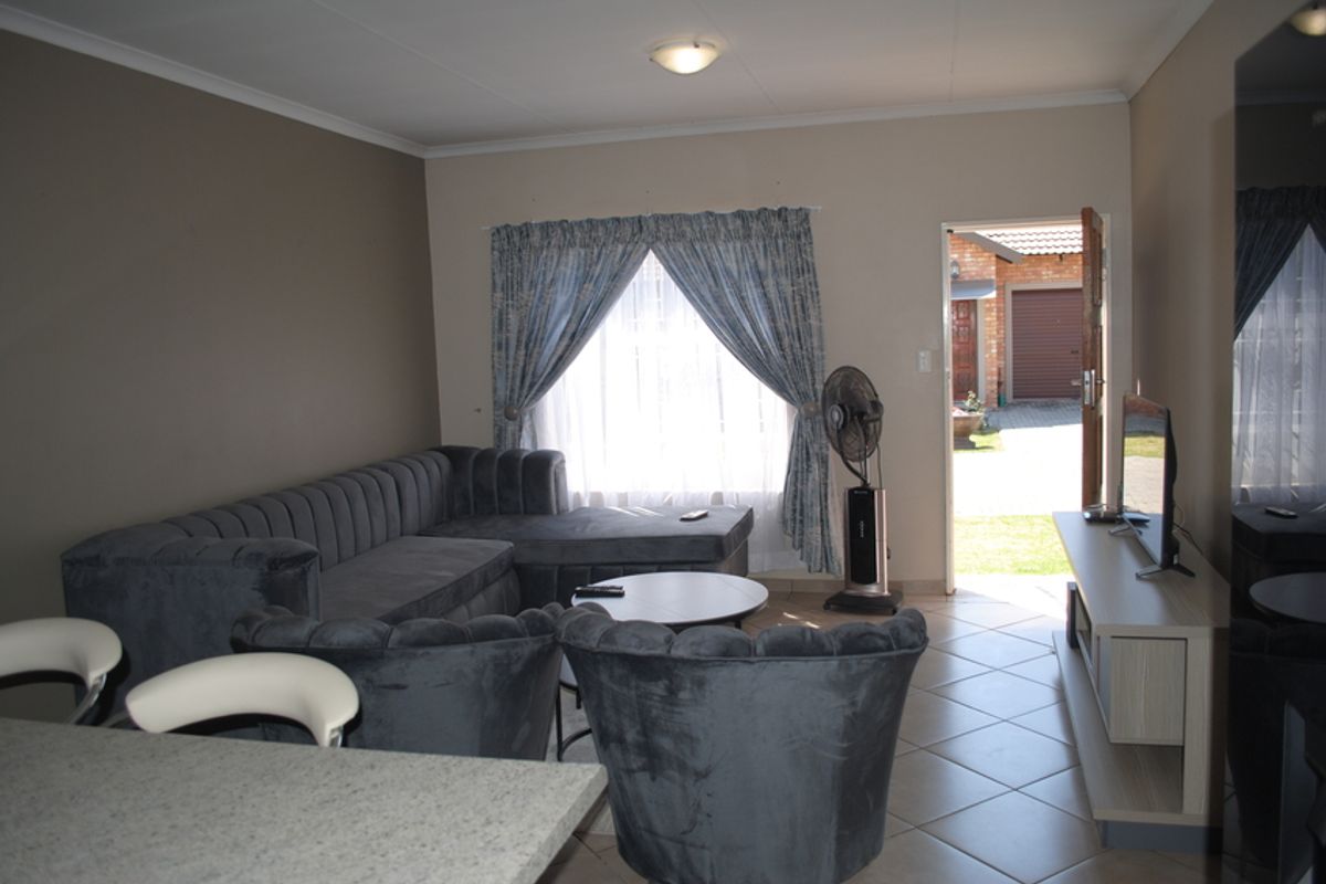 A living room area featuring tiled flooring and direct access to the exterior, providing a functional space with neutral wall tones.