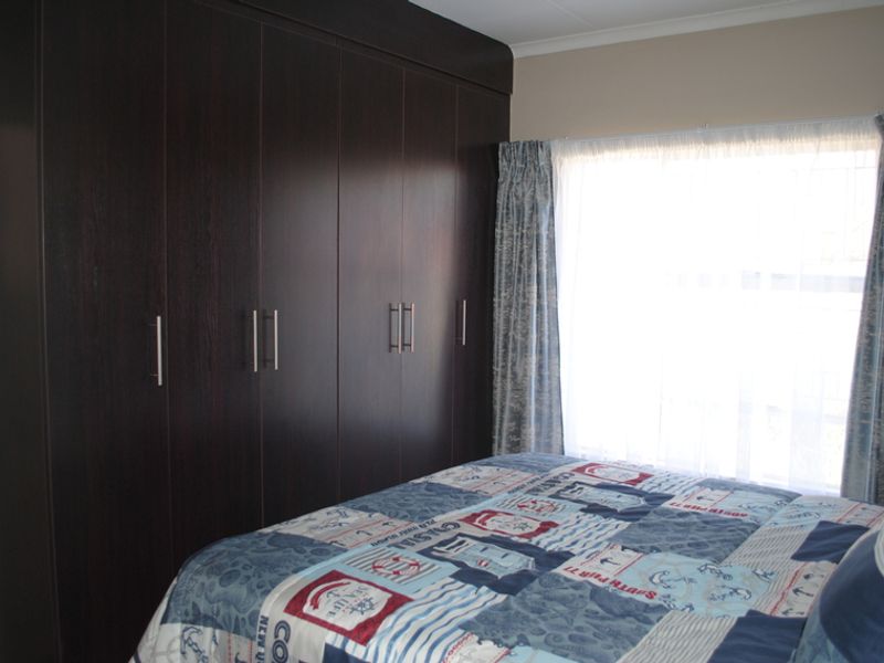 A bedroom featuring dark wood built-in cupboards providing ample storage space and a window allowing natural light.