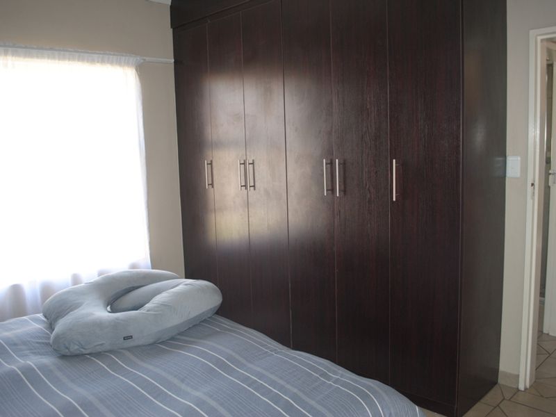 Bedroom featuring dark wood built-in cupboards and natural light from the window.