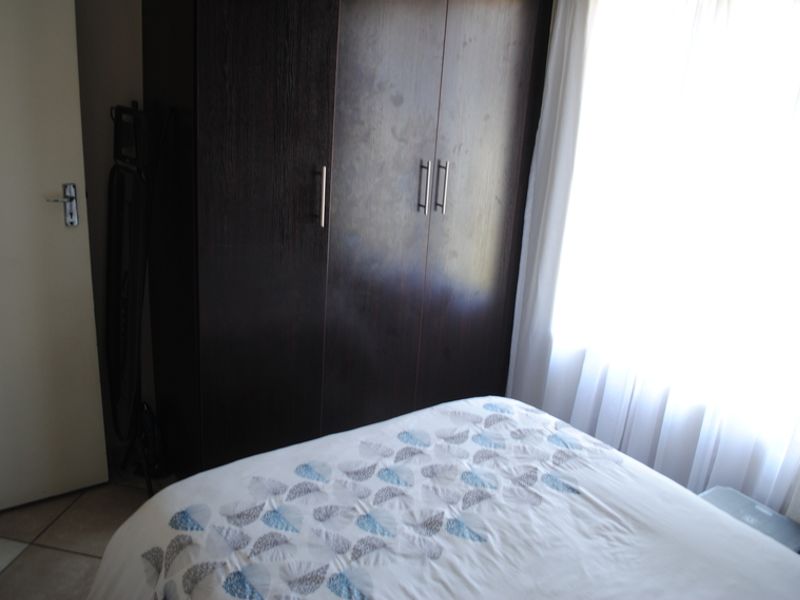 A bedroom featuring dark wood built-in cupboards and natural light from the window.