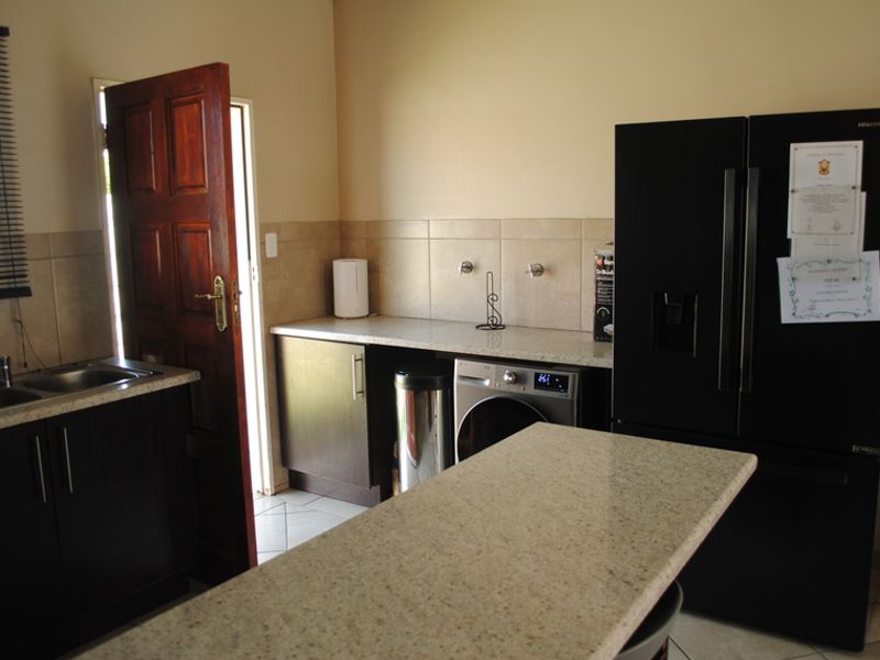 A functional laundry area featuring built-in dark cabinetry, stone countertops, a double sink, and dedicated plumbing connections for appliances.