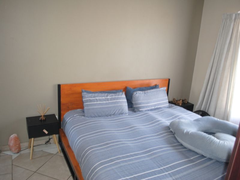 A bedroom featuring neutral wall tones and tiled flooring, providing a functional and comfortable sleeping space.