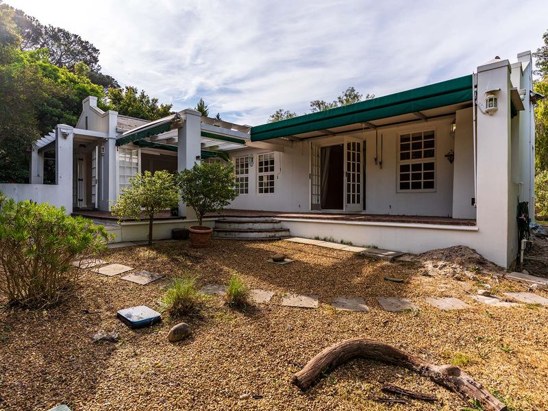 Rear view of the property featuring a covered patio area with retractable awnings, french doors, and a gravel garden setting.