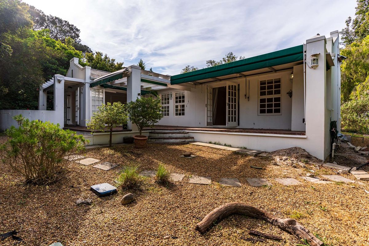Rear view of the property featuring a covered patio area with retractable awnings, french doors, and a gravel garden setting.