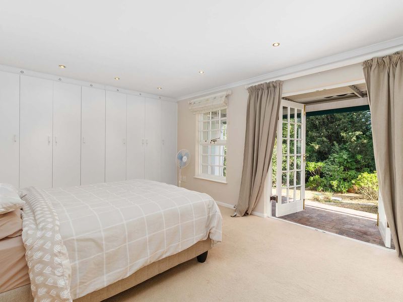 Spacious bedroom featuring extensive built-in cupboards, recessed lighting, and direct access to a private patio through classic French doors.