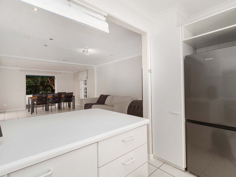 Open plan kitchen and living area featuring white cabinetry, tiled floors, and recessed lighting, creating a bright and functional space.