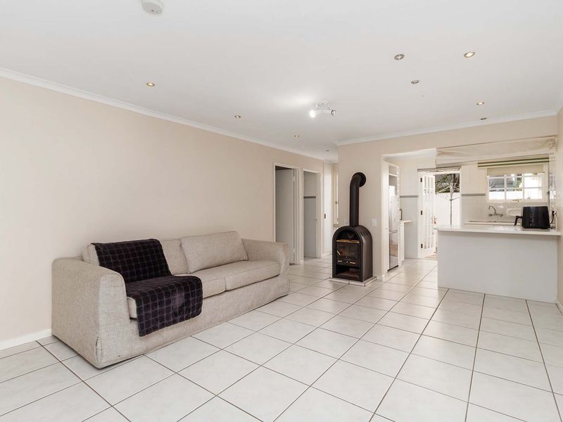 Open-plan living area featuring tiled flooring, a central freestanding fireplace, and a functional kitchen with a breakfast bar.