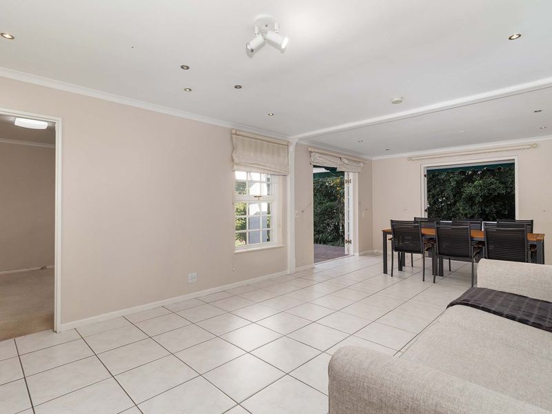 Spacious open-plan living and dining area featuring neutral tiled flooring, recessed lighting, and direct access to the outdoor patio through French doors.