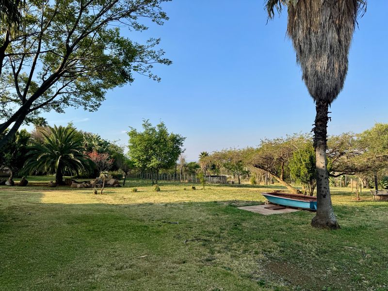 A spacious, well-maintained farm garden featuring mature trees, expansive lawn areas, and established landscaping.