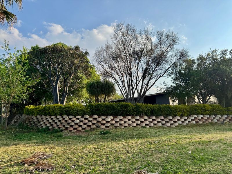 A well-maintained garden area featuring a structured retaining wall and mature trees, providing a pleasant outdoor landscape for the property.