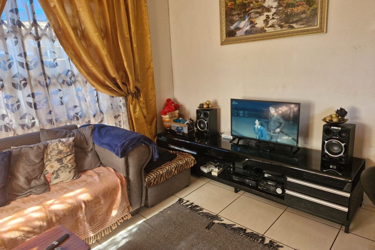 A living room featuring tiled flooring and a window with security gate, providing a functional space for relaxation.