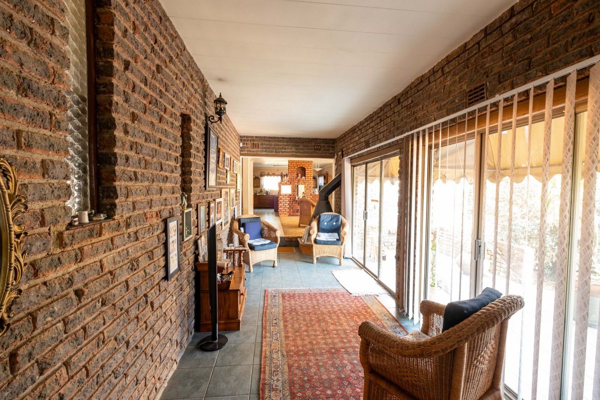 A sunlit living area featuring exposed brick walls, tiled flooring, and large sliding glass doors that provide access to the outdoor space.