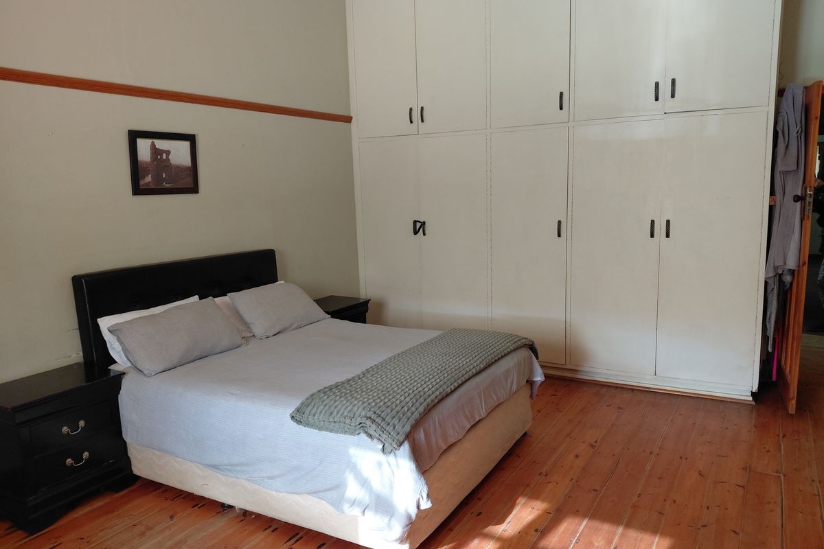 A bedroom featuring polished timber flooring and extensive floor-to-ceiling built-in cabinetry providing ample storage space.