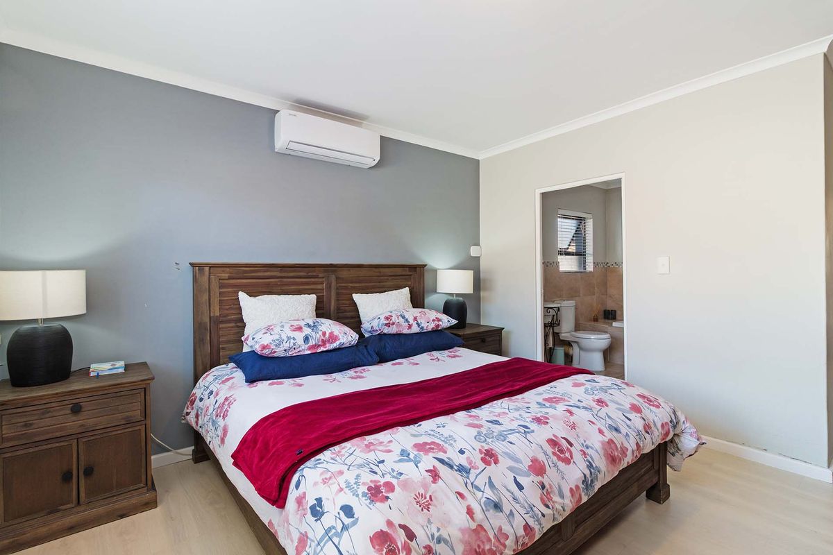 A well-maintained bedroom featuring a split-system air conditioner and direct access to an en-suite bathroom.