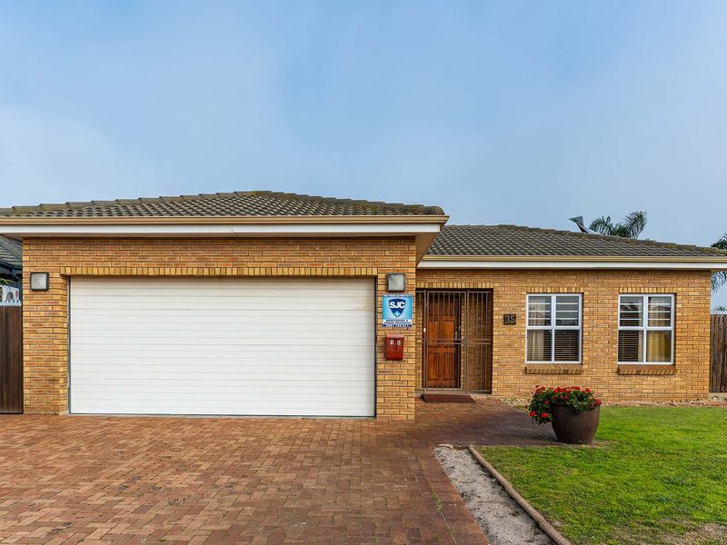 Front elevation of a well-maintained brick house featuring a double garage, paved driveway, and secure entrance with a security gate.