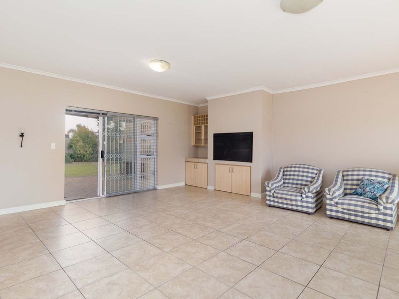 Spacious living room featuring neutral tiled flooring, built-in cabinetry, and a sliding glass door providing direct access to the rear garden.