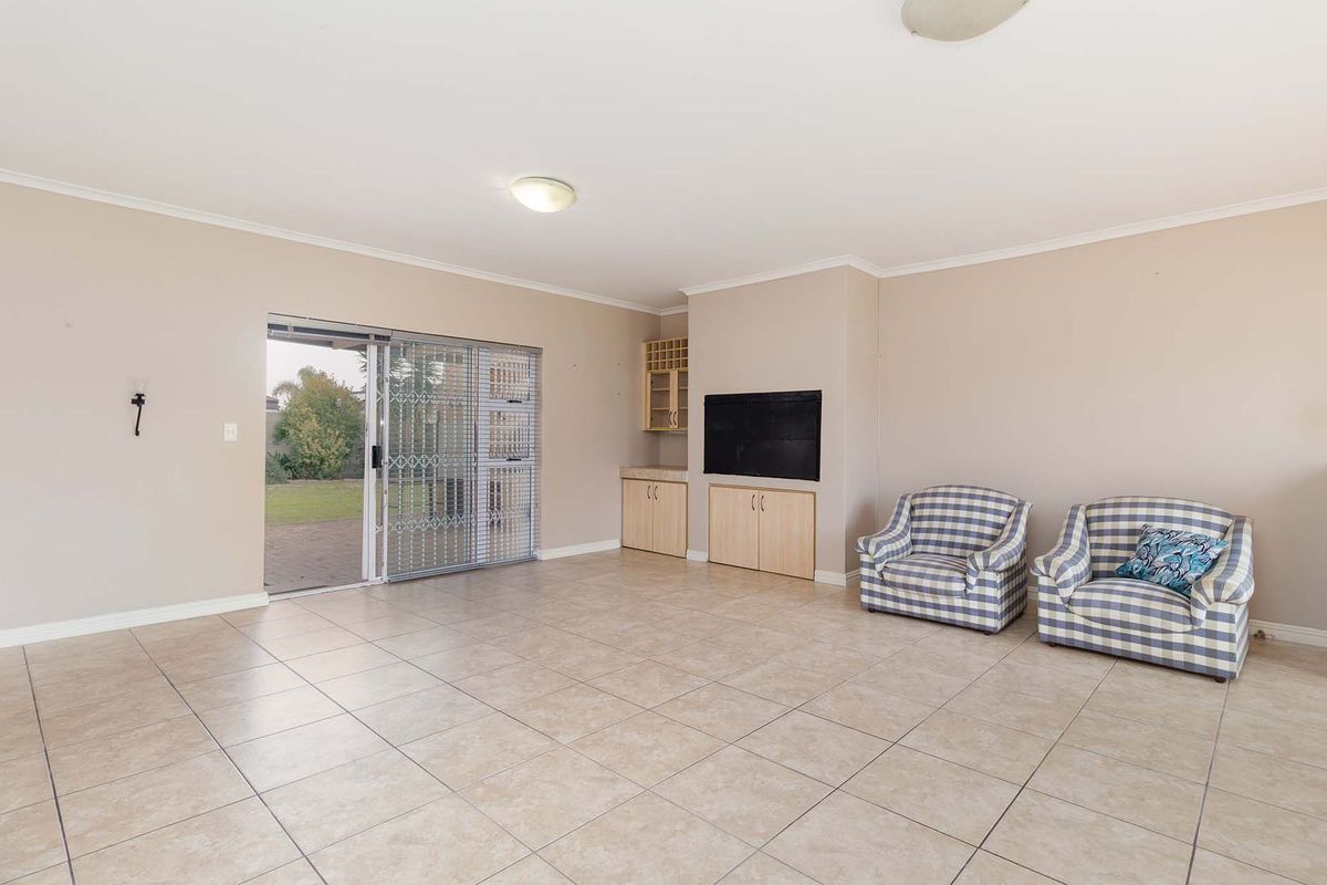 Spacious living room featuring neutral tiled flooring, built-in cabinetry, and a sliding glass door providing direct access to the rear garden.