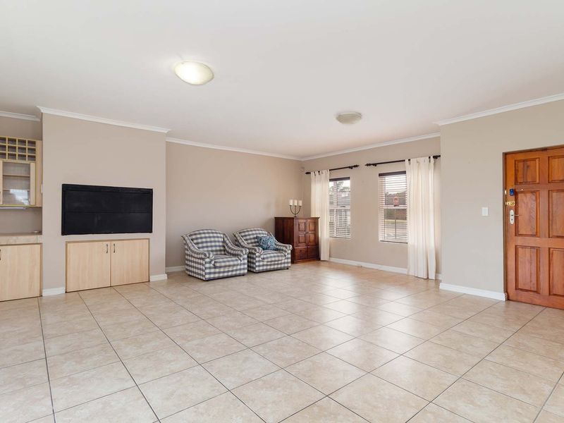 Spacious living area featuring neutral tiled flooring, built-in cabinetry, and a solid timber entrance door, offering a versatile layout for comfortable family living.