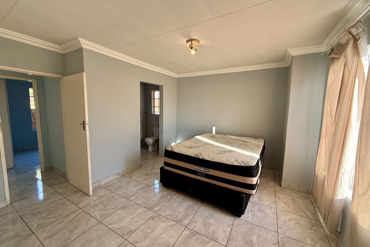 A bedroom featuring tiled flooring, crown molding, and direct access to an en-suite bathroom.