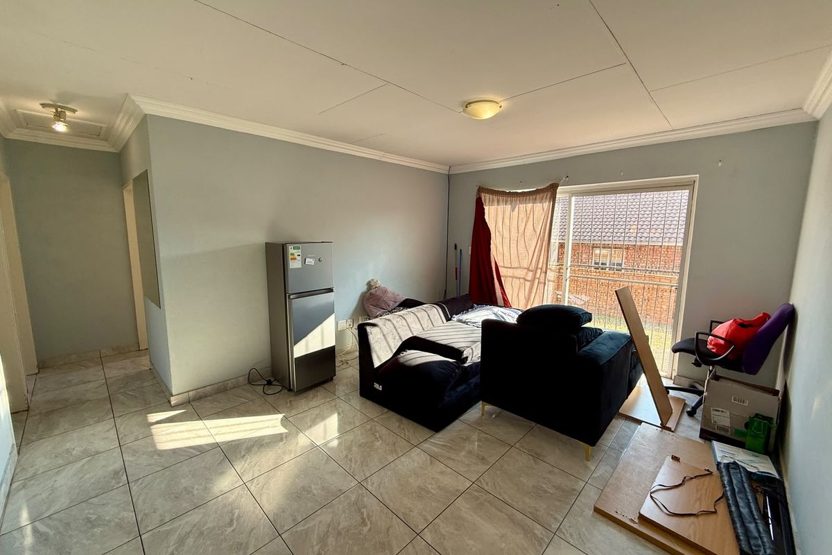 A living area featuring tiled flooring, ceiling cornice detailing, and a sliding glass door providing access to the exterior.