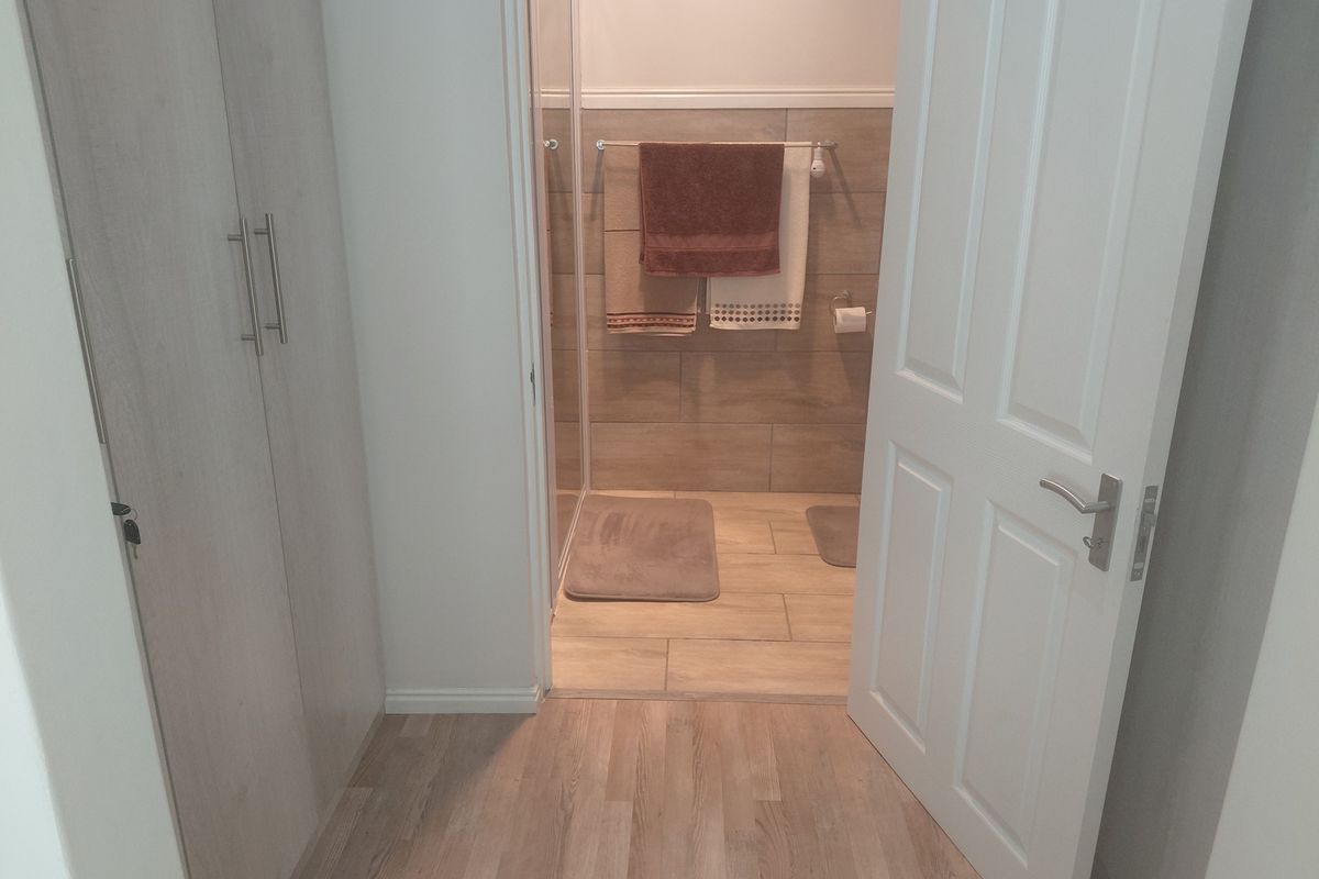 A clean, modern bathroom featuring light wood-look flooring, built-in cabinetry, and a tiled shower enclosure.