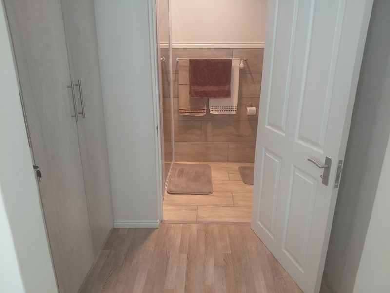 A clean, modern bathroom featuring light wood-look flooring, built-in cabinetry, and a tiled shower enclosure.