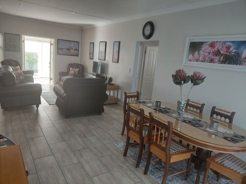 Spacious open-plan living and dining area featuring neutral tiled flooring, recessed lighting, and direct access to an outdoor patio space.