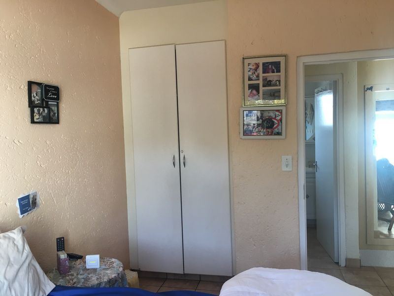 A bedroom featuring a built-in wardrobe and tiled flooring, with access to an adjoining room.