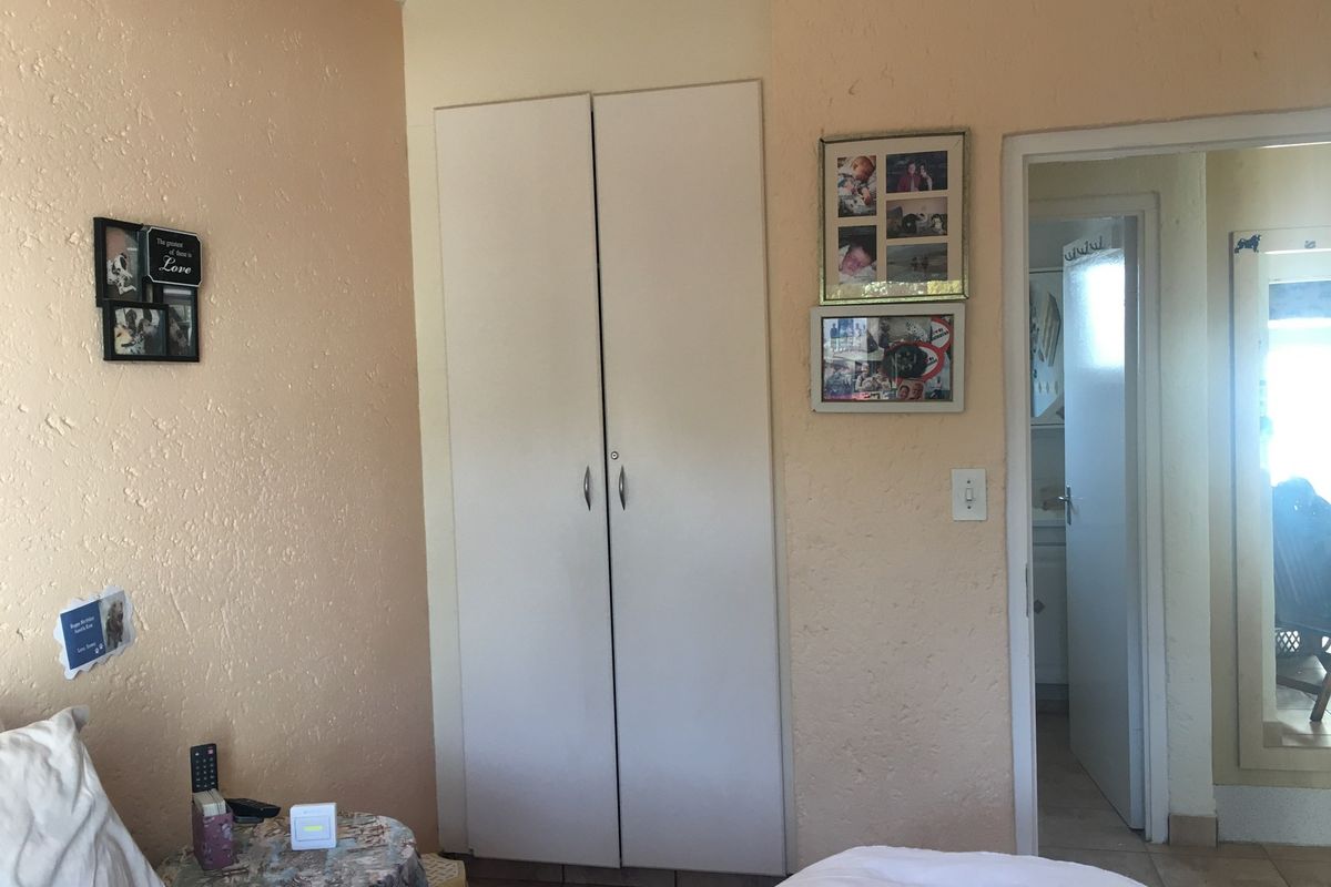A bedroom featuring a built-in wardrobe and tiled flooring, with access to an adjoining room.
