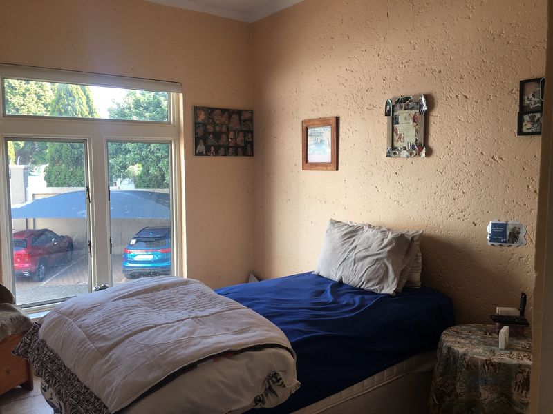 A bedroom featuring a large window with natural light and textured wall finishes, providing a functional space for rest.