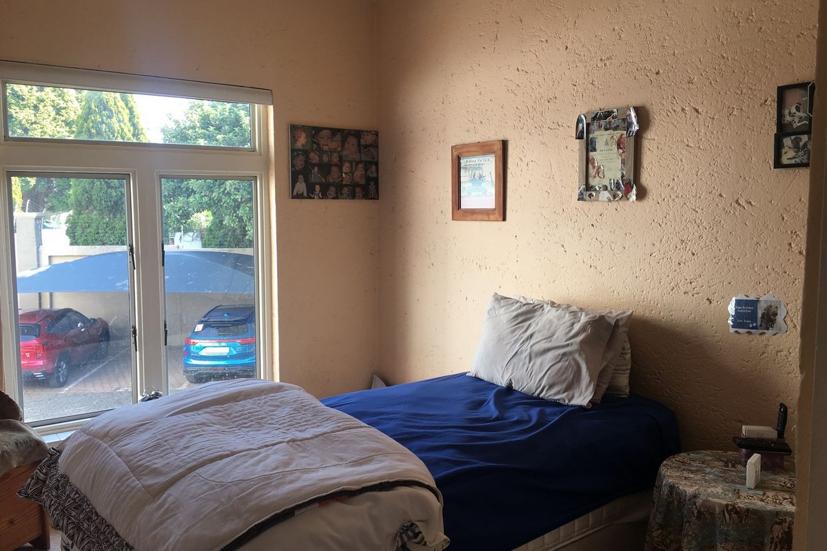 A bedroom featuring a large window with natural light and textured wall finishes, providing a functional space for rest.