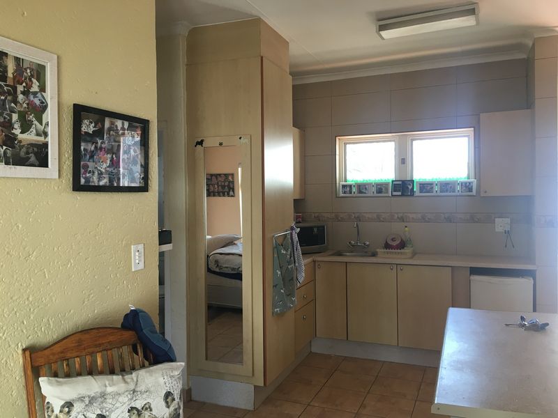A functional kitchen featuring built-in cabinetry, tiled backsplash, and tiled flooring, offering a practical layout with potential for modern cosmetic updates.