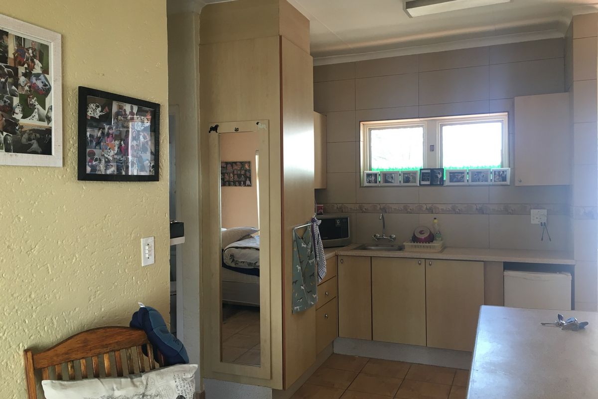 A functional kitchen featuring built-in cabinetry, tiled backsplash, and tiled flooring, offering a practical layout with potential for modern cosmetic updates.