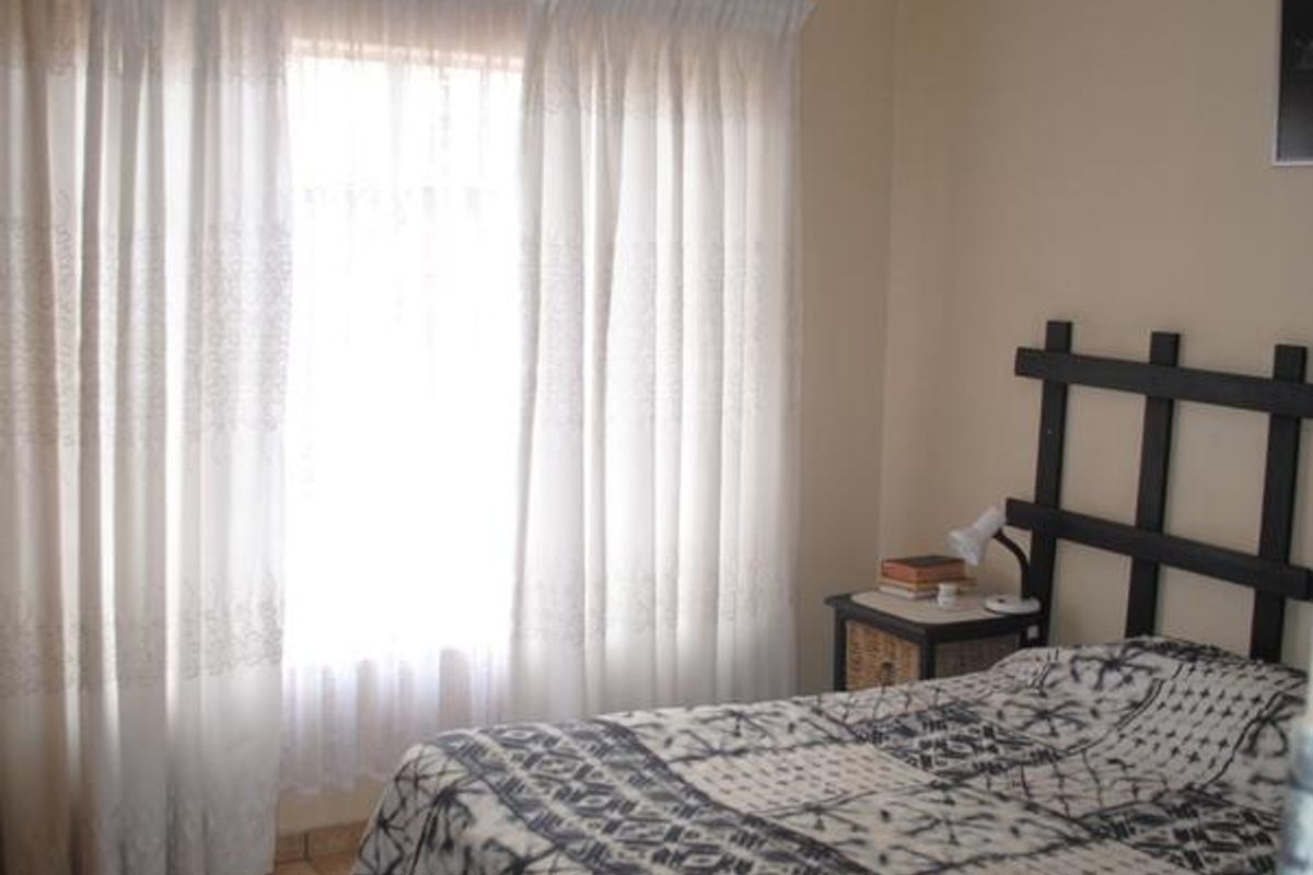 A functional bedroom featuring tiled flooring and recessed ceiling lighting, offering a neutral base for personalization.