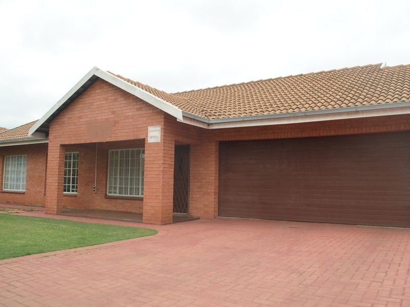 A well-maintained face brick house featuring a tiled roof, paved driveway, and an integrated double garage with a secure entrance.