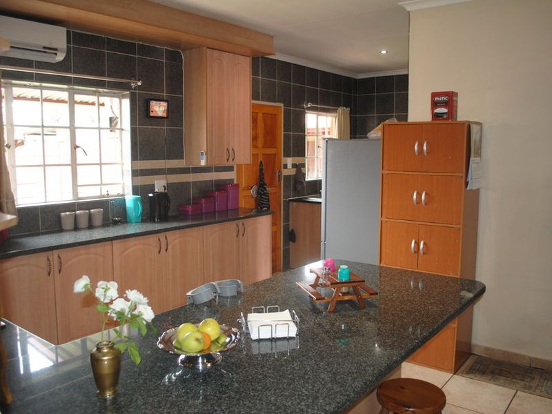 A functional kitchen featuring granite countertops, laminate cabinetry, and a tiled backsplash, providing a practical workspace with integrated air conditioning.