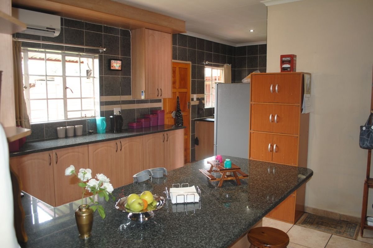 A functional kitchen featuring granite countertops, laminate cabinetry, and a tiled backsplash, providing a practical workspace with integrated air conditioning.